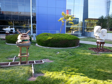 Statues in park at the center of Google campus. Most of them are white statues of significant people but one is not.