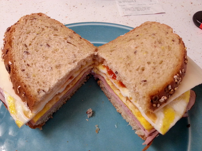 My breakfast/snack special: a sandwich with eggs, ham, cheese, and some ketchup.